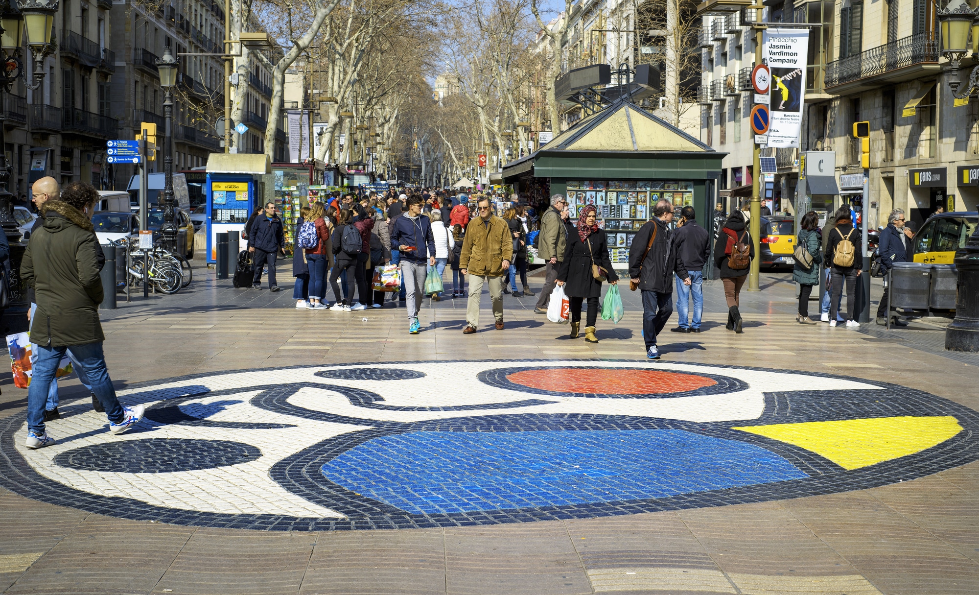 Gente paseando en la Rambla de Barcelona con mural de Miró en el suelo